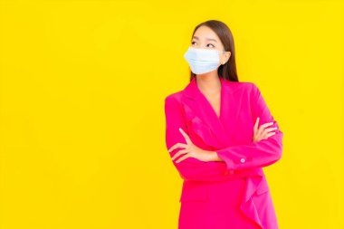 Güzel bir Asyalı kadın koronavirüsü korumak için maske takıyor ya da sarı arka planda 19 numara giyiyor.