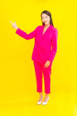 Sarı arka planda çağrı merkezi teması için kulaklığı ve kulaklığı olan güzel Asyalı kadın portresi