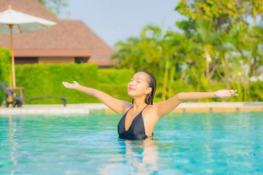 Güzel bir Asyalı kadın portresi. Rahatlayın, gülümseyin. Tatil için oteldeki yüzme havuzunun keyfini çıkarın.