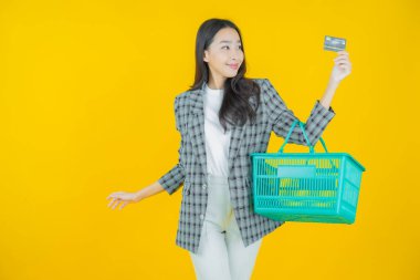 Renkli arka planda süpermarketten alınmış market sepetiyle gülümseyen güzel Asyalı kadın portresi.