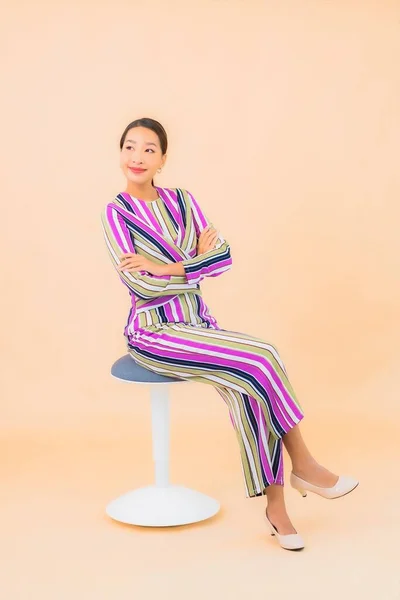 亚洲年轻貌美的女子坐在椅子上 微笑着 在与肤色隔离的背景上采取行动 — 图库照片