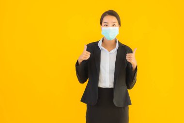 Güzel genç iş kadını portresi Korunmak için maske takıyor 19 koronavirüs sarı izole arka planda