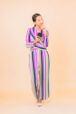 Güzel bir Asyalı kadın portresi izole edilmiş arka planda akıllı cep telefonu kullanır.