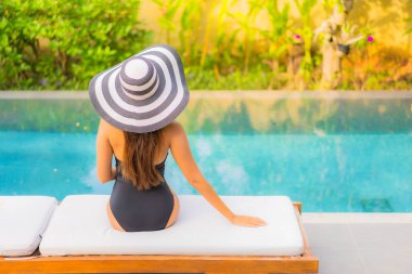 Güzel bir Asyalı kadının portresi tatil için yüzme havuzunda rahatlıyor.