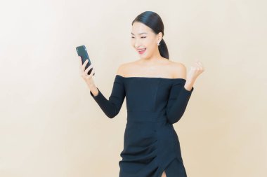 Renkli arka planda akıllı cep telefonuyla güzel Asyalı kadın gülümsemesi