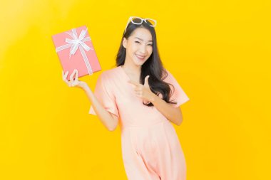 Güzel bir Asyalı kadının portresi. Arka planda kırmızı hediye kutusuyla gülümsüyor.