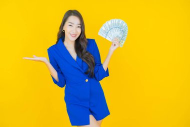 Asyalı güzel bir kadının portresi. Renkli arka planda bol para ve parayla gülümsüyor.