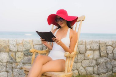 Portre genç Asyalı kadın seyahat tatilinde deniz kenarında kitap okudu.