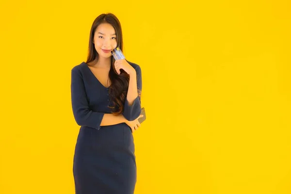 스마트폰이나 신용카드 노란색외진 배경을 아름다운 아시아 여성의 — 스톡 사진