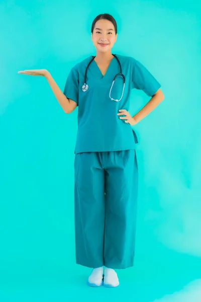 ポートレート美しい若いアジアの医師の女性幸せな笑顔のために病院やクリニックでの仕事上の青隔離された背景 — ストック写真