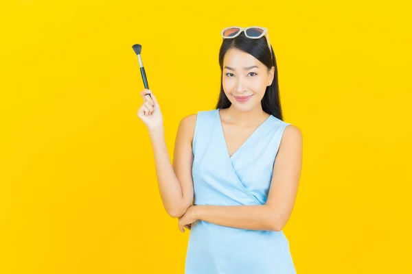 Portret Piękna Młoda Azjatycka Kobieta Makijaż Pędzel Kosmetyk Żółtym Tle — Zdjęcie stockowe