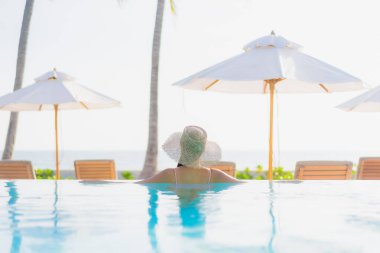 Güzel bir Asyalı kadın portresi. Tatil gezisinde deniz manzaralı açık havuz etrafında rahatça yüzebiliyor.