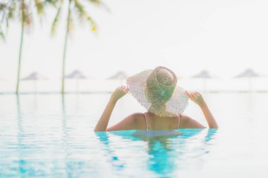 Güzel bir Asyalı kadın portresi. Tatil gezisinde deniz manzaralı açık havuz etrafında rahatça yüzebiliyor.