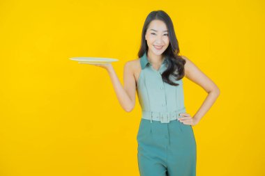 Güzel Asyalı bir kadının portresi. Arka planda boş tabak tabağıyla gülümsüyor.