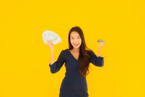 肖像画美しいです若いですアジアの女性とともに現金とクレジットカード上の黄色隔離された背景 — ストック写真