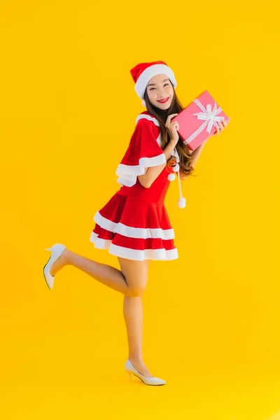 年轻美丽的亚洲圣诞服装和帽子笑着与黄色孤立背景的红色礼品盒 — 图库照片