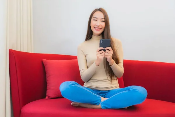 肖像画美しい若いアジアの女性使用スマートフォン上のソファの上にリビングルームのインテリア — ストック写真