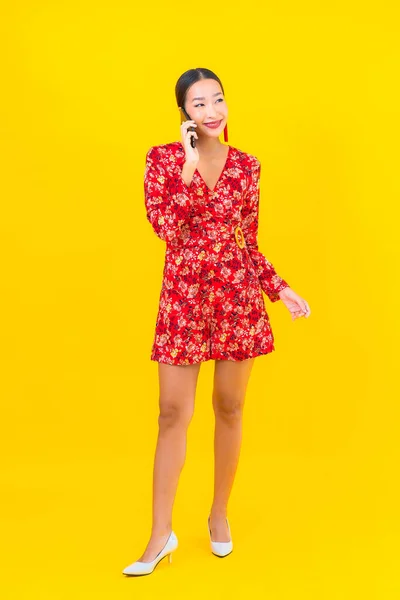 Güzel Bir Asyalı Kadın Sarı Arka Planda Akıllı Cep Telefonu — Stok fotoğraf