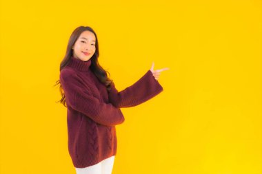 Güzel Asyalı kadın gülümsüyor. Sarı izole edilmiş arka planda başka bir eylemde mutlu.