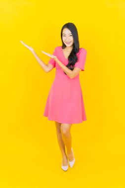 Asyalı güzel bir kadının portresi. Sarı arka planda hareketli gülümsüyor.