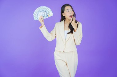 Asyalı güzel bir kadının portresi. Renkli arka planda bol para ve parayla gülümsüyor.