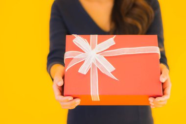 Sarı izole edilmiş arka planda hediye kutusu olan güzel Asyalı kadın portresi.