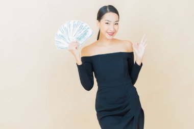 Asyalı güzel bir kadının portresi. Renkli arka planda bol para ve parayla gülümsüyor.