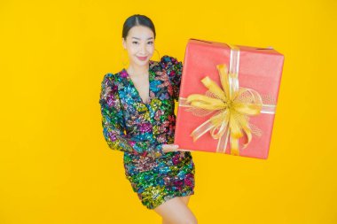 Güzel bir Asyalı kadının portresi. Arka planda kırmızı hediye kutusuyla gülümsüyor.