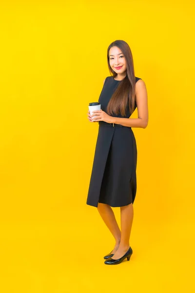 拥有咖啡杯和黄色背景智能手机的漂亮年轻亚洲女商人形象 — 图库照片