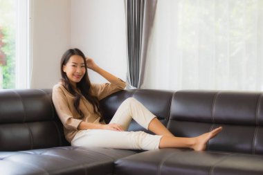 Güzel bir Asyalı kadın portresi. Mutlu bir gülümseme. Oturma odasındaki kanepede rahatla.