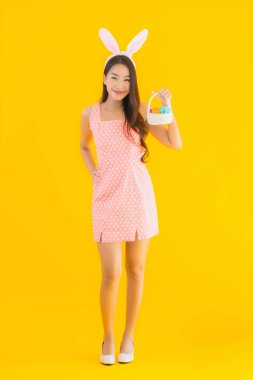 Paskalya yumurtaları sepette, sarı izole edilmiş arka planda tavşan kulaklı güzel Asyalı kadın portresi.