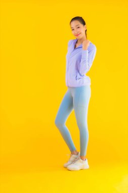 Sarı izole edilmiş arka planda spor giysili güzel Asyalı kadın portresi egzersize hazır.