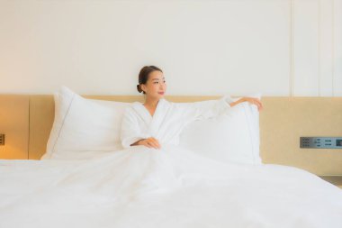 Güzel bir Asyalı kadın portresi. Rahatlayın, gülümseyin. Yatak odasında dinlenin.