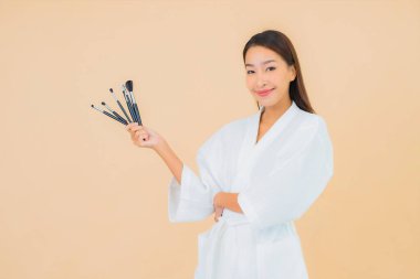 Renkli arka planda makyaj fırçası olan güzel bir Asyalı kadın portresi.
