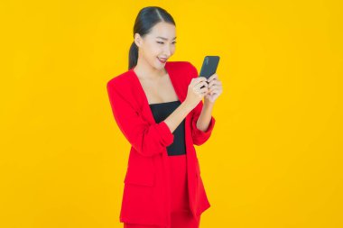 Renkli arka planda akıllı cep telefonuyla güzel Asyalı kadın gülümsemesi