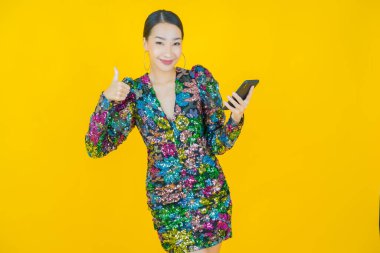 Renkli arka planda akıllı cep telefonuyla güzel Asyalı kadın gülümsemesi