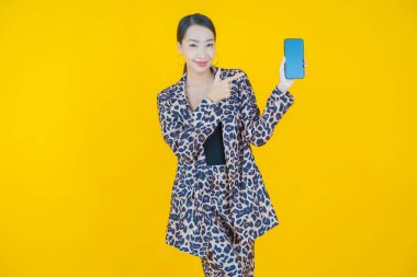 Renkli arka planda akıllı cep telefonuyla güzel Asyalı kadın gülümsemesi