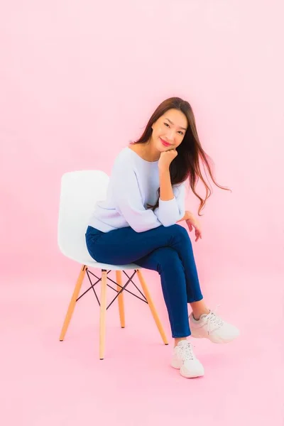 Portrait beautiful young asian woman sit on chair with pink color background