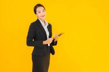 Güzel, genç Asyalı bir kadının portresi mutlu bir gülümseme ve sarı izole edilmiş arka planda akıllı tabletler.