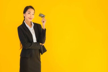 Sarı izole edilmiş arka planda kredi kartı olan güzel, genç Asyalı kadın portresi.