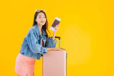 Çantalı güzel Asyalı kadın. Pasaportu ve sarı izole bir arka planda bilet.