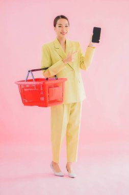 Renkli arka planda süpermarketten alınmış market sepetiyle güzel bir Asyalı kadın portresi.