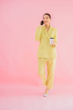 Güzel Asyalı iş kadını portresi. Arka planda kahve fincanı ve akıllı cep telefonu kullanıyor.