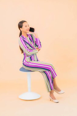 Güzel bir Asyalı kadın portresi izole edilmiş arka planda akıllı cep telefonu kullanır.