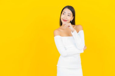 Portre güzel genç iş kadını gülümseyen ve eylem sarı arka planlı Asyalı kadın