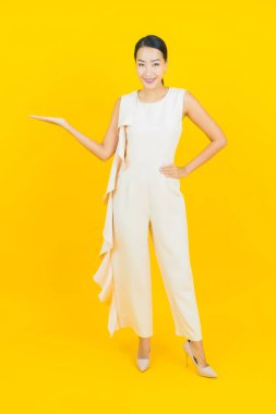 Asyalı güzel bir kadının portresi. Sarı arka planda hareketli gülümsüyor.