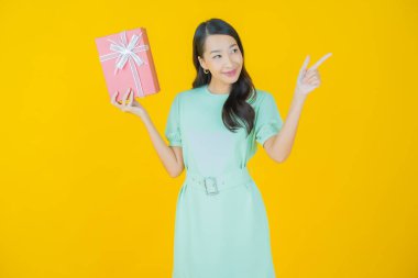 Güzel bir Asyalı kadının portresi. Arka planda kırmızı hediye kutusuyla gülümsüyor.