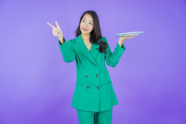 Güzel Asyalı bir kadının portresi. Arka planda boş tabak tabağıyla gülümsüyor.