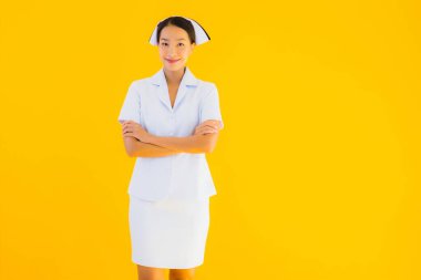 Güzel Asyalı genç Taylandlı hemşirenin portresi klinikteki ve hastanedeki hastalar için sarı izole edilmiş arka planda birçok eylem çalışmasında yer alıyor.