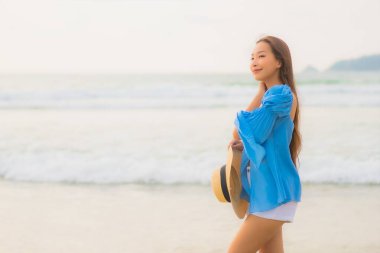 Güzel bir Asyalı kadın portresi. Gün batımında deniz kıyısında rahatça gülümse.